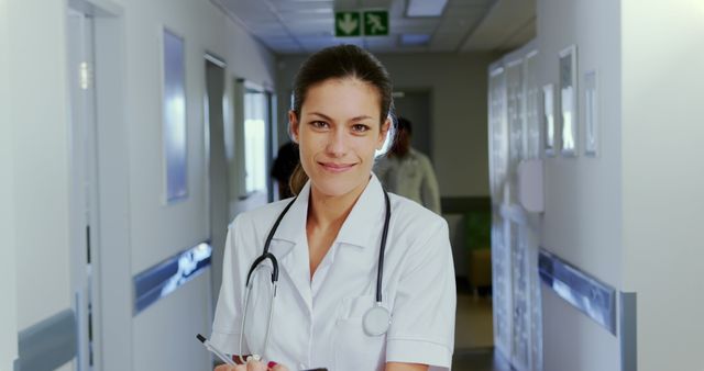 Smiling Female Healthcare Worker in Hospital Corridor with Clipboard and Stethoscope - Download Free Stock Images Pikwizard.com