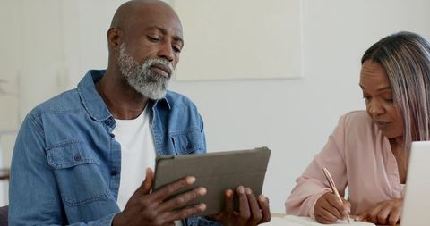 Mature Black Couple Managing Household Finances With Tablet and Written Notes