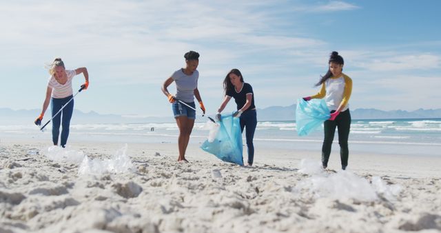 Diverse group of female friends putting rubbish in refuse sacks at the beach. eco conservation volunteers, beach clean-up.