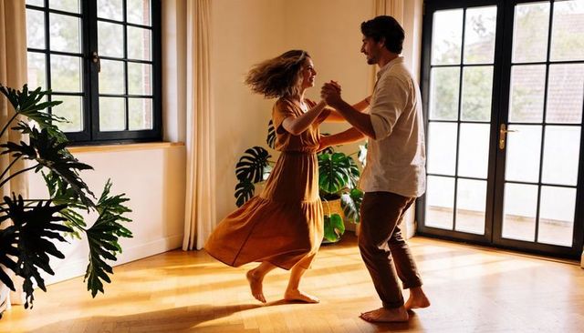 Sunlit barefoot couple dancing in living room, mustard dress twirling on parquet floor