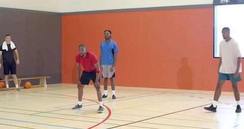 Defending player holding low stance during pickup basketball game on indoor court