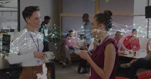 Colleagues networking with innovative technology in office lounge