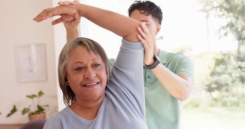 Senior Woman Receiving Arm Stretch Therapy from Physiotherapist
