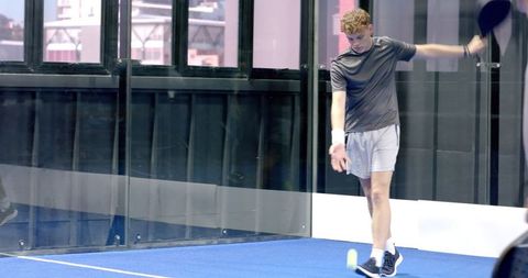 Young Man Playing Padel on Indoor Blue Turf Court