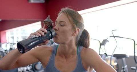 Fit Young Woman Drinking Water in Gym Highlighting Hydration
