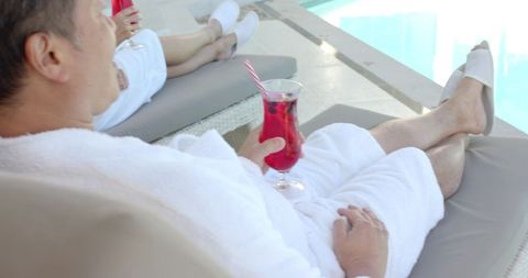 Seniors Relaxing Poolside in Robes with Refreshing Cocktails