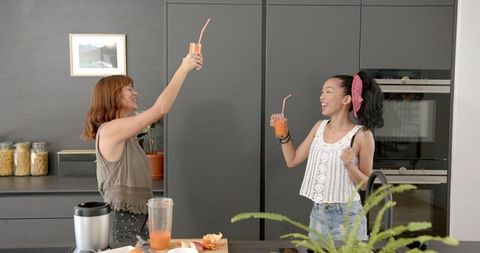Joyful Friends Sharing Orange Juice in Modern Kitchen