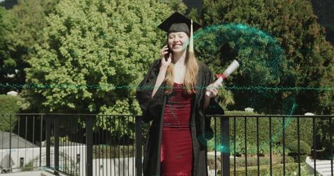 Young Graduate Celebrating on Campus Balcony Wearing Gown and Mortarboard Holding Diploma