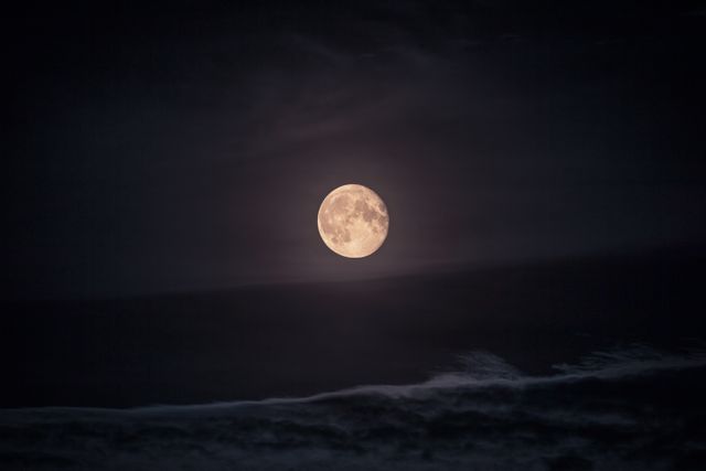 This serene scene captures a full moon illuminating a dark night sky. The image can be used for astronomy blogs, night sky photography websites, nature article illustrations, and calming themed backgrounds.