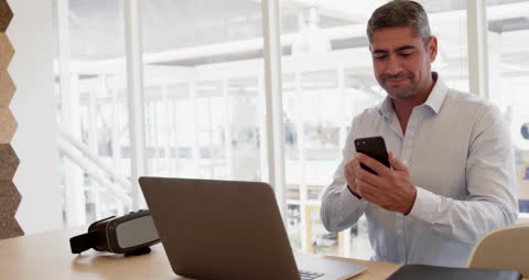 Mature Businessman Multitasking in Modern Office