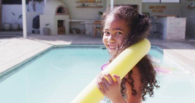 Portrait of happy biracial girl looking at camera at swimming pool. domestic lifestyle, spending free time at home.