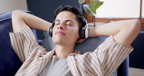 Relaxed Young Man Enjoys Music with Headphones on Cozy Couch