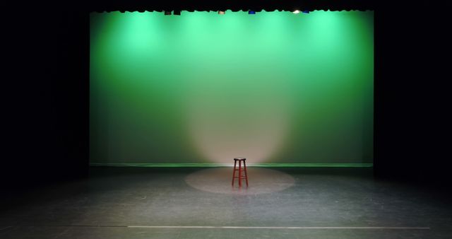 An empty stage with a single red chair under a spotlight, with copy space. The scene evokes anticipation for a performance or presentation in a theater setting.