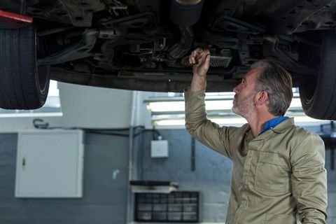 Experiencing Mechanic Analyzing Under Raised Car for Repairs