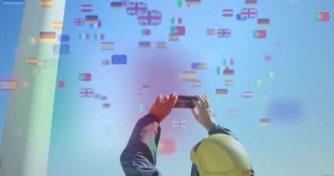 Worker in safety helmet capturing international flag projection at industrial expo