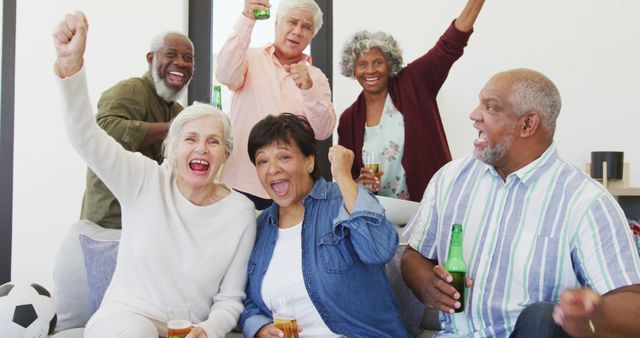 Portrait of happy senior diverse people watching tv with beer at retirement home. healthy, active retirement and body inclusivity.