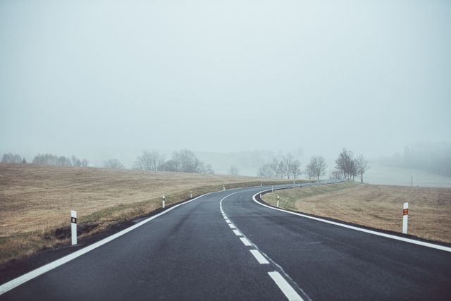 Empty country road on foggy morning with gentle curves - Download Free Stock Photos Pikwizard.com