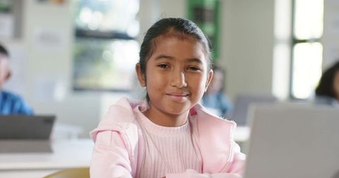 Young student smiling while using laptop in classroom for digital learning and education