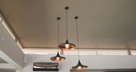 Three copper pendant lamps hanging in minimalist contemporary lounge with clerestory light
