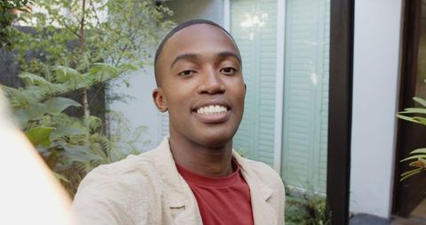 Smiling man taking selfie in lush garden courtyard