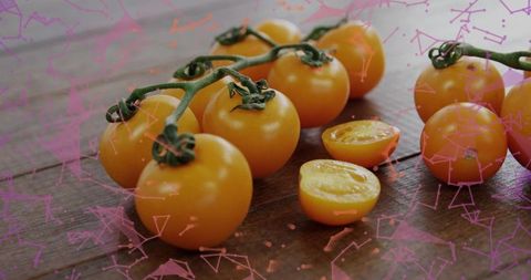 Orange cherry tomato vine macro on rustic wood table with halved tomatoes and pink overlay