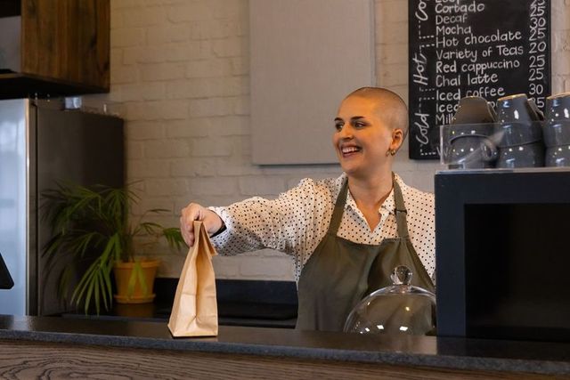 Smiling female barista handing takeaway bag at cozy cafe counter