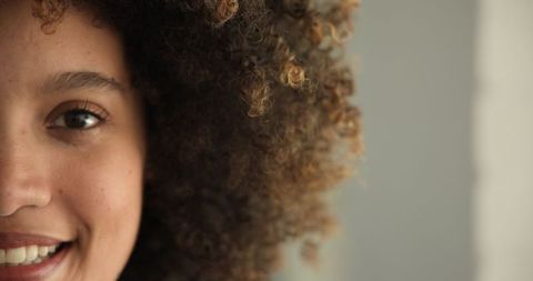 Smiling Woman Highlighting Natural Curly Hair and Warm Expression