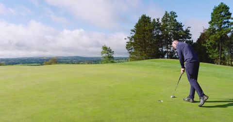 Man Putting on Tranquil Golf Course under Clear Skies
