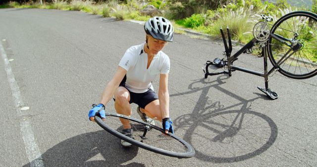 Cyclist fixing flat tire on road while on cycling trip - Download Free Stock Images Pikwizard.com