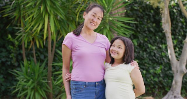 Image of happy asian mother and daughter embracing in garden. Family, motherhood, relations and spending quality time together concept digitally generated image.