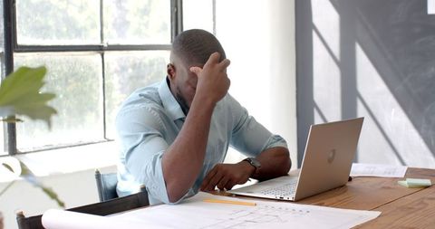 Frustrated architect reviewing blueprints in modern office