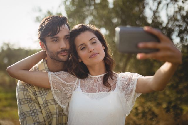 Beautiful young woman taking selfie with man on sunny day