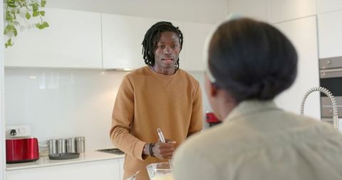 African american couple cooking in modern kitchen man whisking batter while partner watches