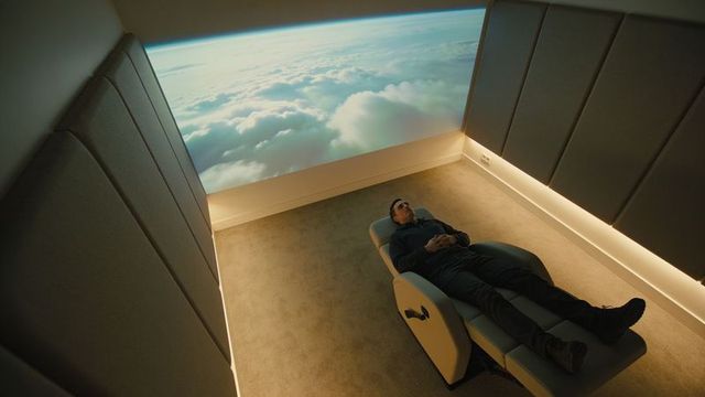 Man reclining in minimalist lounge watching immersive cloud projection for relaxation