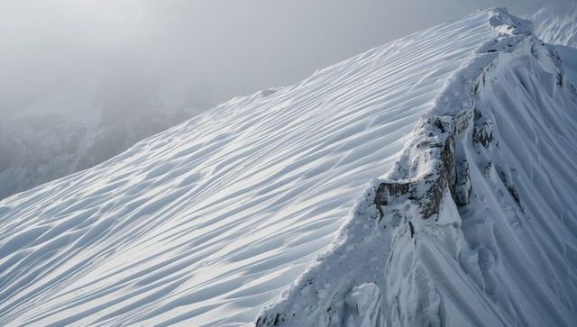 Windswept Alpine Ridge Sculpting Snow Ridges and Cornices with Misty High-Altitude Light