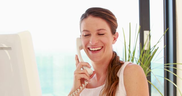 Smiling Woman Talking on Landline Phone at Office Desk - Download Free Stock Images Pikwizard.com