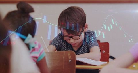 Writing schoolboy wearing glasses at desk with learning analytics overlay and focus