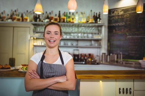 Smiling Barista in Rustic Cafe with Shelves of Liquor Bottles