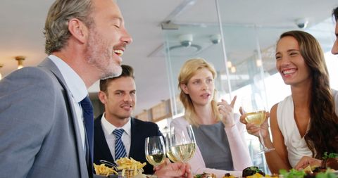 Business Colleagues Dining and Sharing Laughter in Modern Restaurant