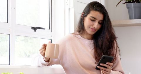 Woman Relaxing by Window with Coffee and Smartphone