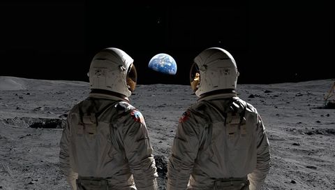 Astronauts watching earthrise on moon surface with lander and gold visors