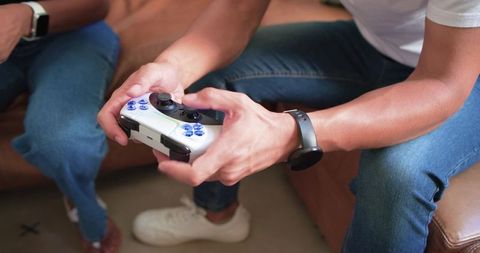 African american couple playing video games on couch holding white controller, relaxed