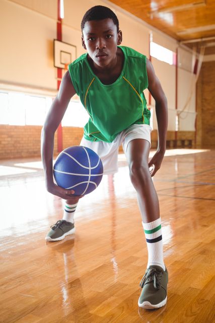 Portrait of teenage boy playing basketball in court