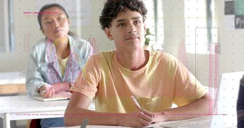 Curly teen taking notes in classroom, learning with digital data overlay and charts