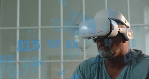 Senior man wearing vr headset exploring holographic finance data in modern home office