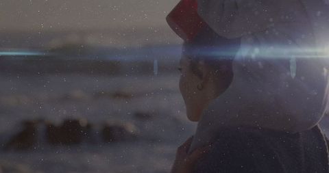 Woman in red headband reflects by snowy coast at dusk