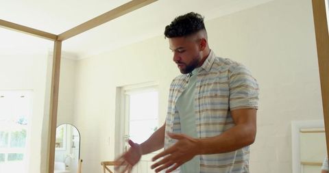 Man Showcasing Modern Four-Poster Bed in Minimalist Bedroom