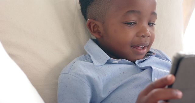 Smiling Child Relaxing on Couch and Using Smartphone - Download Free Stock Images Pikwizard.com