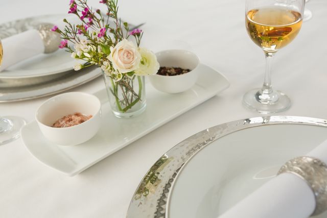 Elegant table setting featuring a delicate floral arrangement, wine glasses, and fine dining elements. Perfect for illustrating special occasions, romantic dinners, celebrations, or luxury dining experiences. Ideal for use in hospitality, event planning, and lifestyle content.