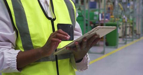 Plant Technician in Safety Vest Using Tablet in Industrial Factory
